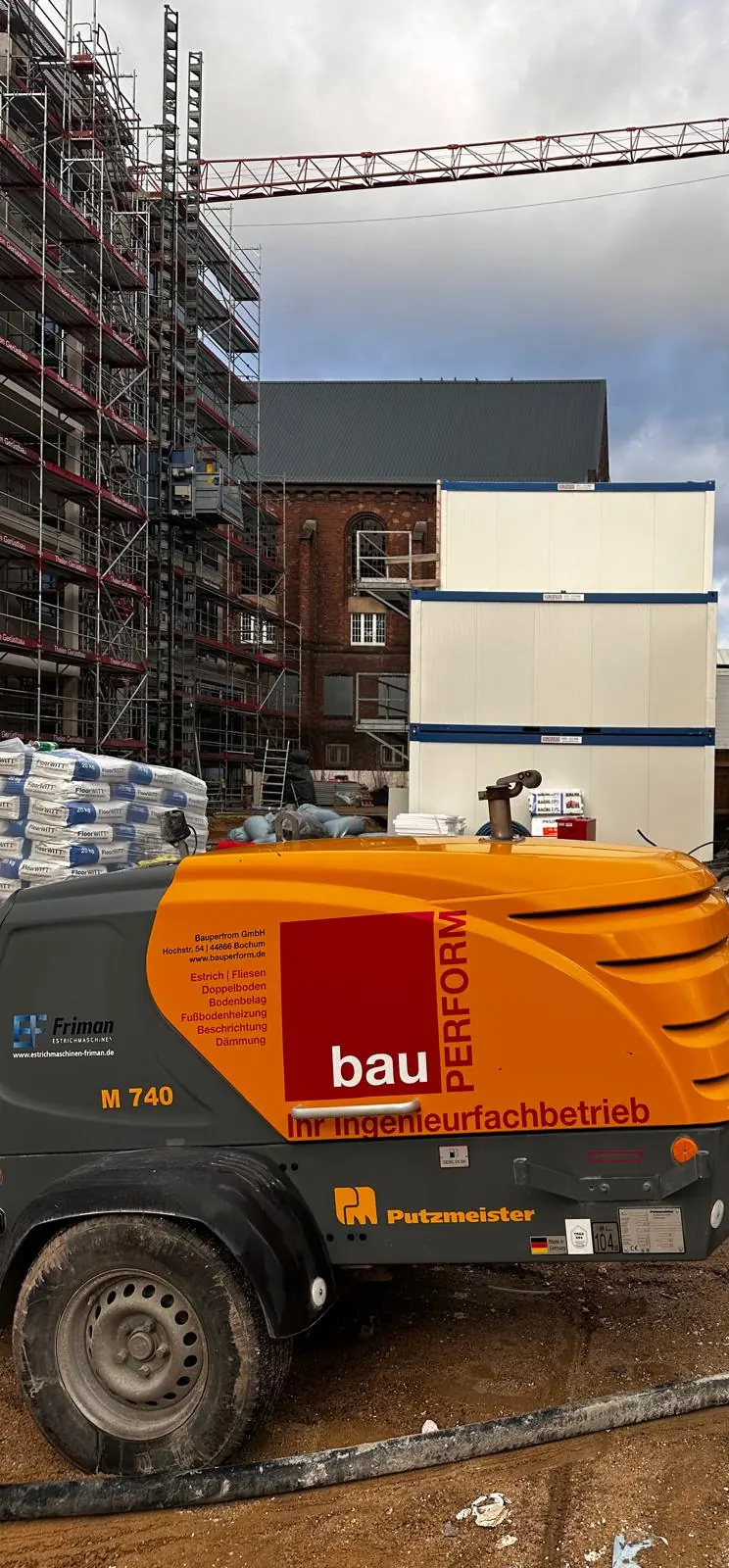 Estrichpumpe von BauPerform vor einem eingerüsteten Rohbau