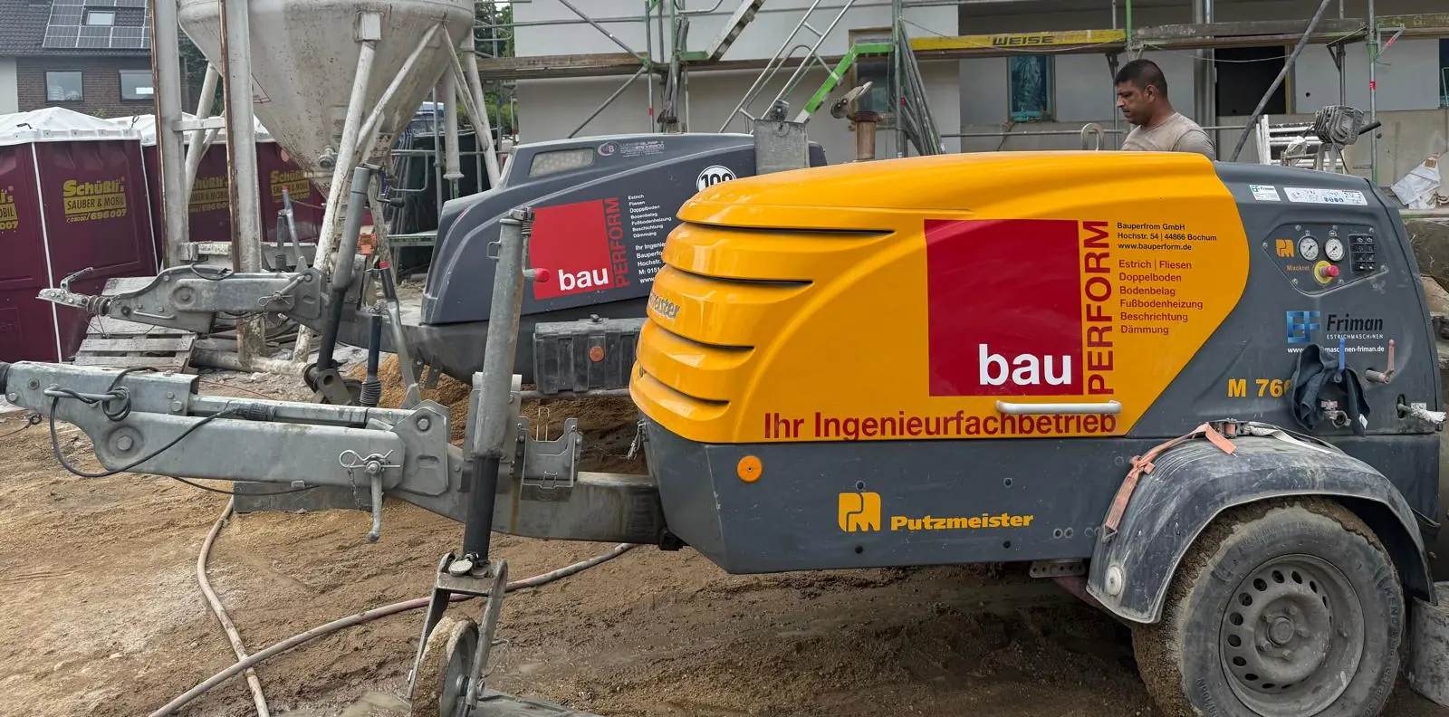 Bindemittelsilo und Estrichpumpe von BauPerform vor einem Rohbau