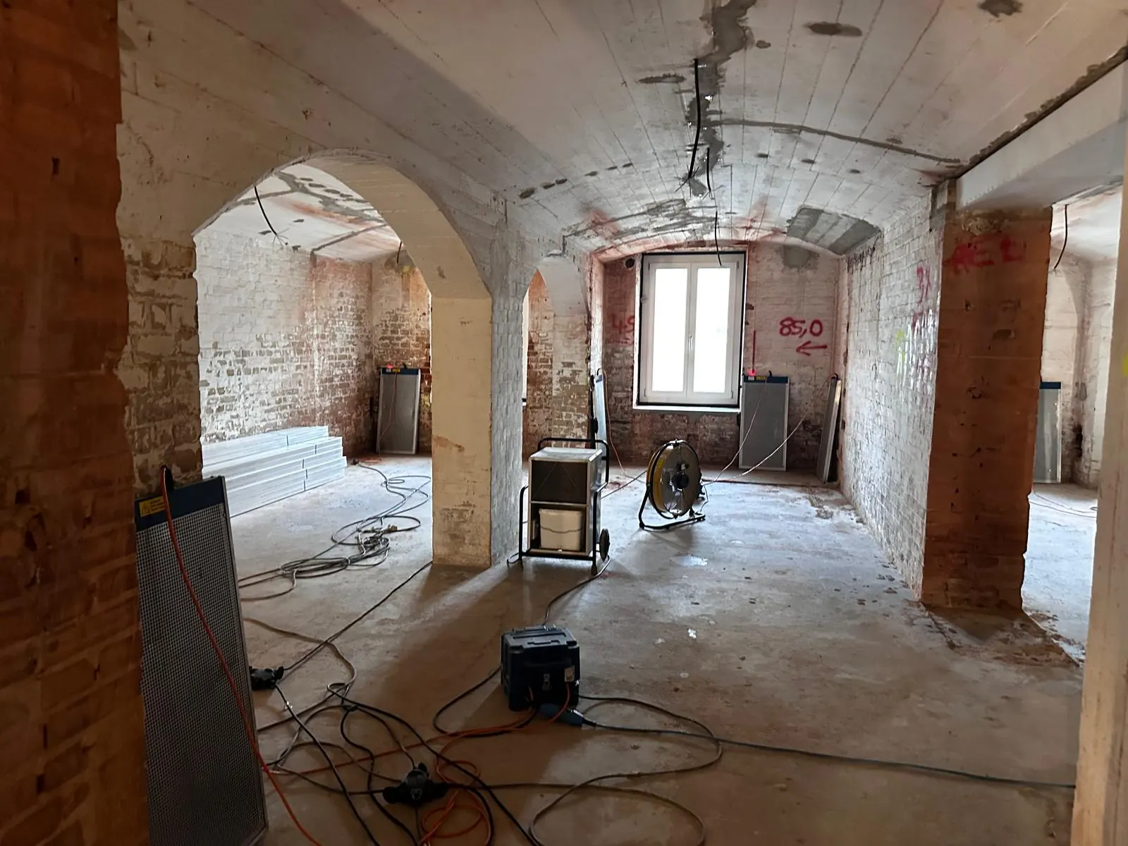 Gewölbegang im Rohzustand mit aufgestellten Bautrocknern und Ventilatoren