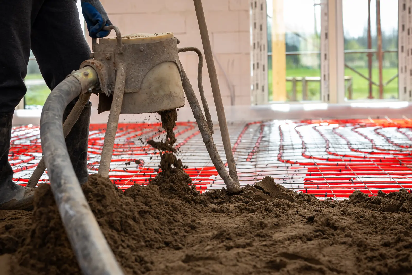 Estrich wird über bereits verlegten Heizrohren eingebracht