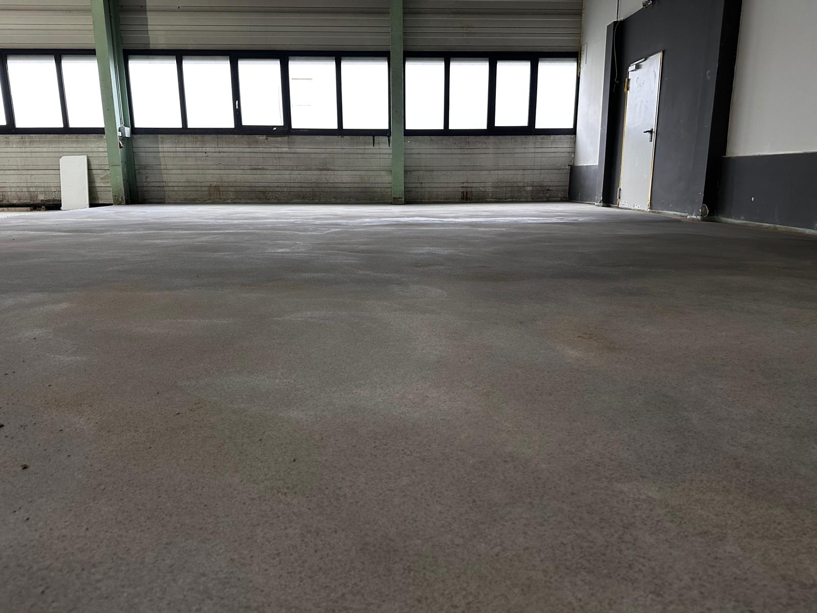 Fertige, geglättete Estrichfläche in einer Halle mit Fensterband, keine sichtbaren Ansätze