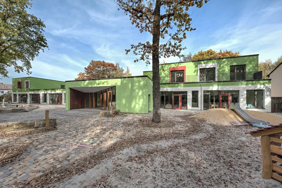 Kindertagesstätte in Dreieich nach der Fertigstellung, grüner Baukörper mit Außenspielfläche