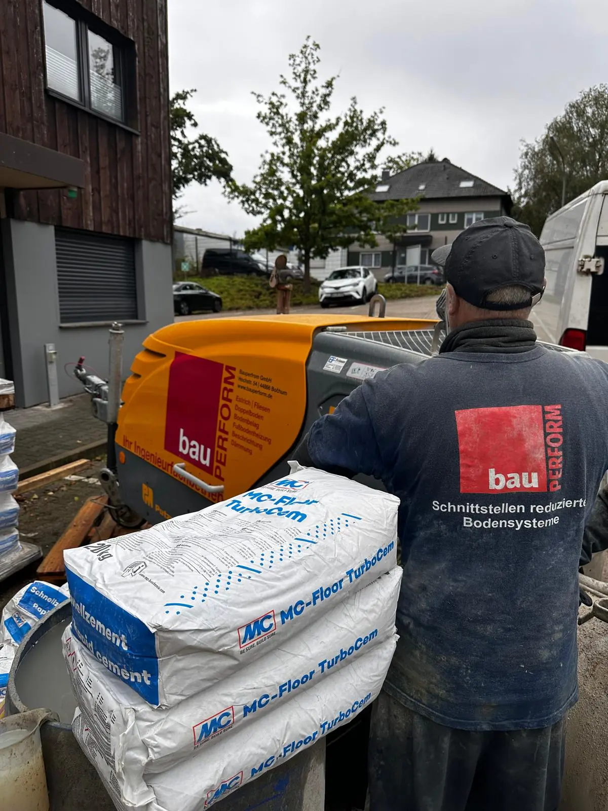 Mitarbeiter mit BauPerform-Arbeitskleidung an der eigenen Estrichpumpe