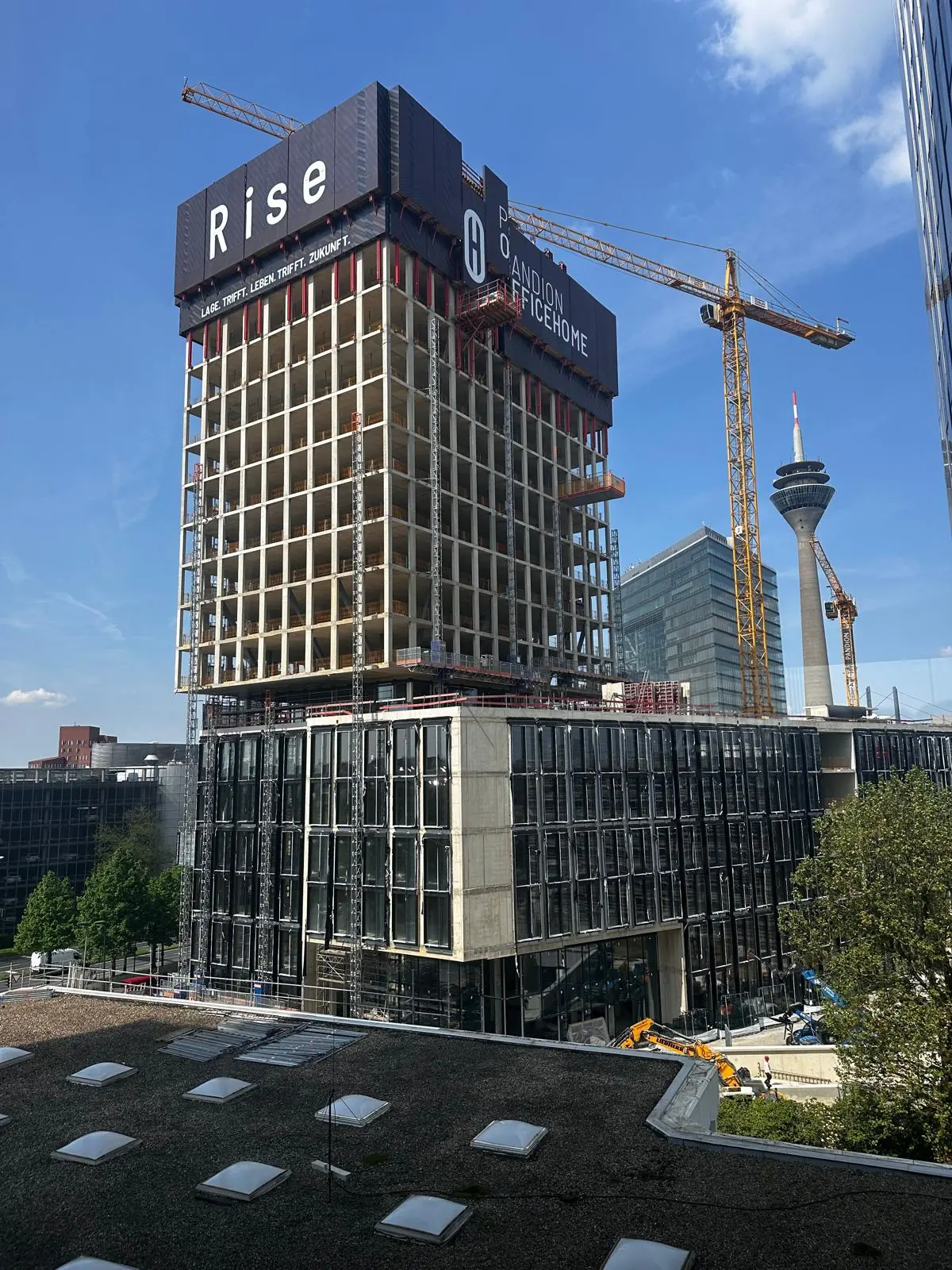 Rohbau des Pandion-Hochhauses mit Schriftzug Rise, dahinter der Rheinturm